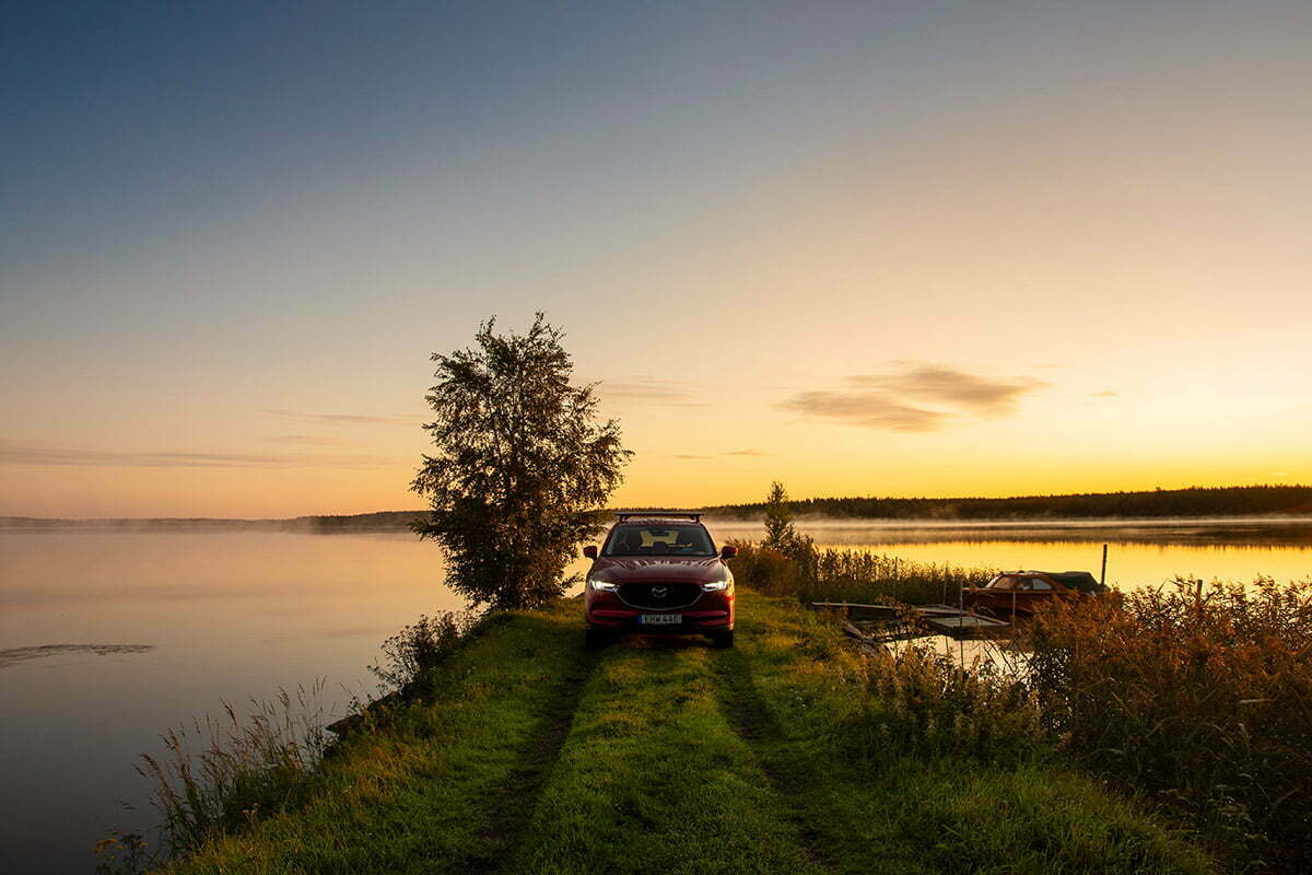 Mazda med kajak och gryning vid en sjö
