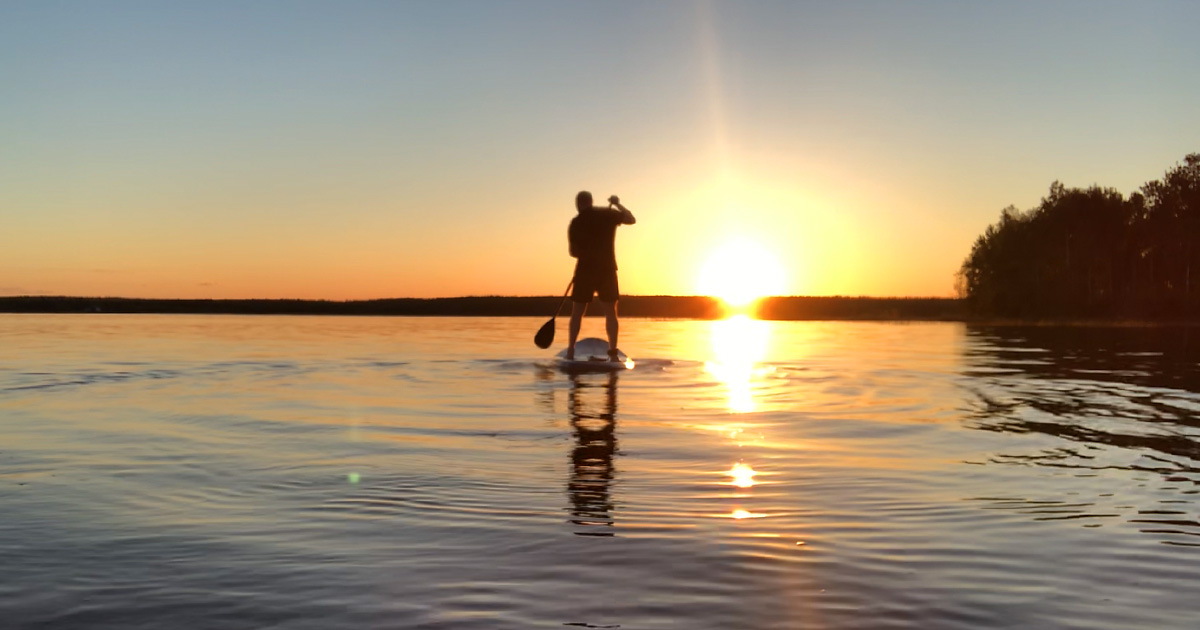 SUP Stand Up Paddling i solnedgång spegelblankt vatten